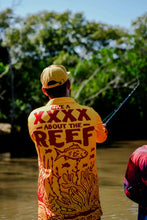 Load image into Gallery viewer, Person fishing in a bright yellow Tide x XXXX collab jersey promoting reef protection.