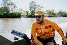 Load image into Gallery viewer, Man wearing Tide x XXXX collab fishing shirt on a boat, enjoying a sunny day on the water.