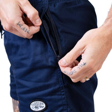 Load image into Gallery viewer, Man's hands unzipping pockets on navy shorts from Yabbies, designed for comfort and utility.